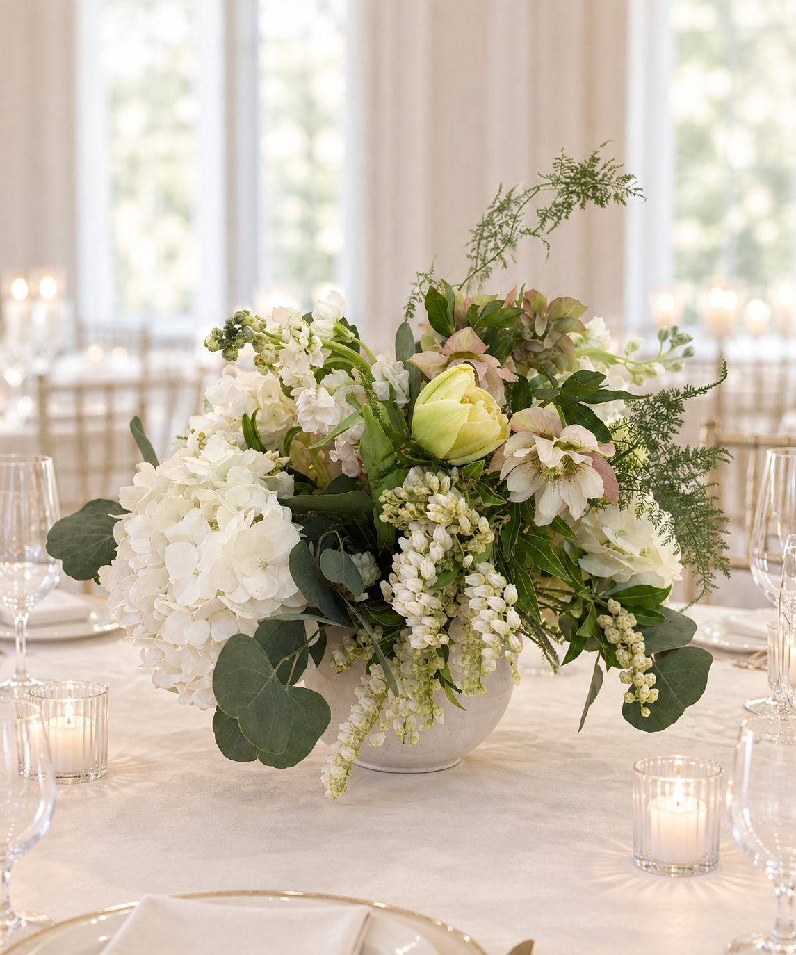 Elegant white hydrangea and hellebore centerpiece in stone vessel